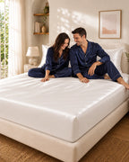 Couple complice assis sur un drap housse blanc en soie de mûrier