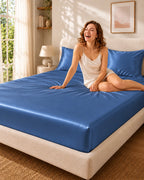 Femme souriante assise sur un drap housse bleu foncé en soie de mûrier