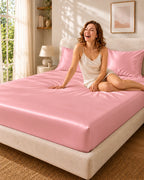 Femme souriante assise sur un drap housse rose en soie de mûrier