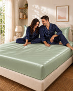 Couple complice assis sur un drap housse vert clair en soie de mûrier