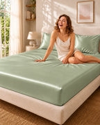 Femme souriante assise sur un drap housse vert clair en soie de mûrier