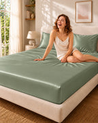 Femme souriante assise sur un drap housse vert foncé en soie de mûrier