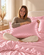 Femme assise sur son lit avec une taie d'oreiller rose en soie de mûrier